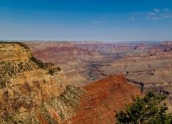 Breathtaking panoramic view of Grand Canyon's dramatic cliffs and valleys under clear skies.