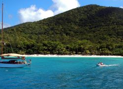 Scenic view of a sailboat and motorboat near the shore of St. John's lush beaches, perfect for a tropical vacation.